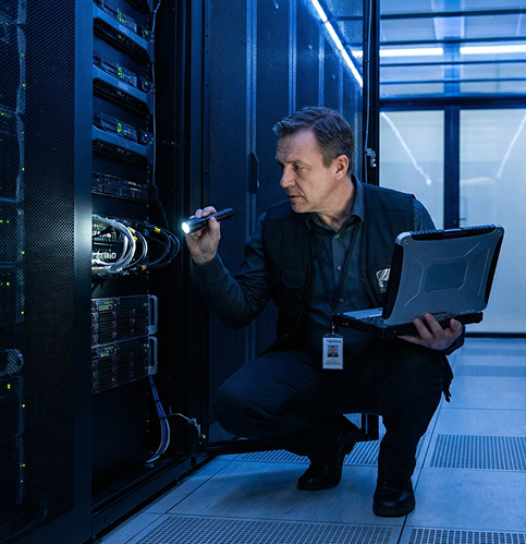 técnico especializado no centro de dados a olhar para o servidor com um portátil